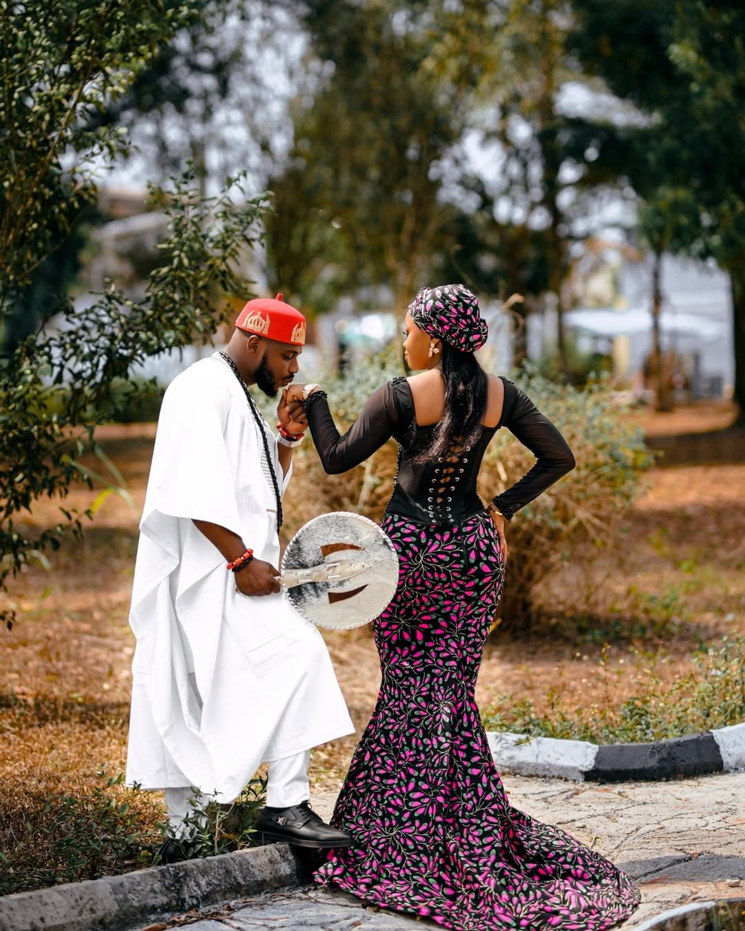 Couple in white attire with patterned black gown outdoors